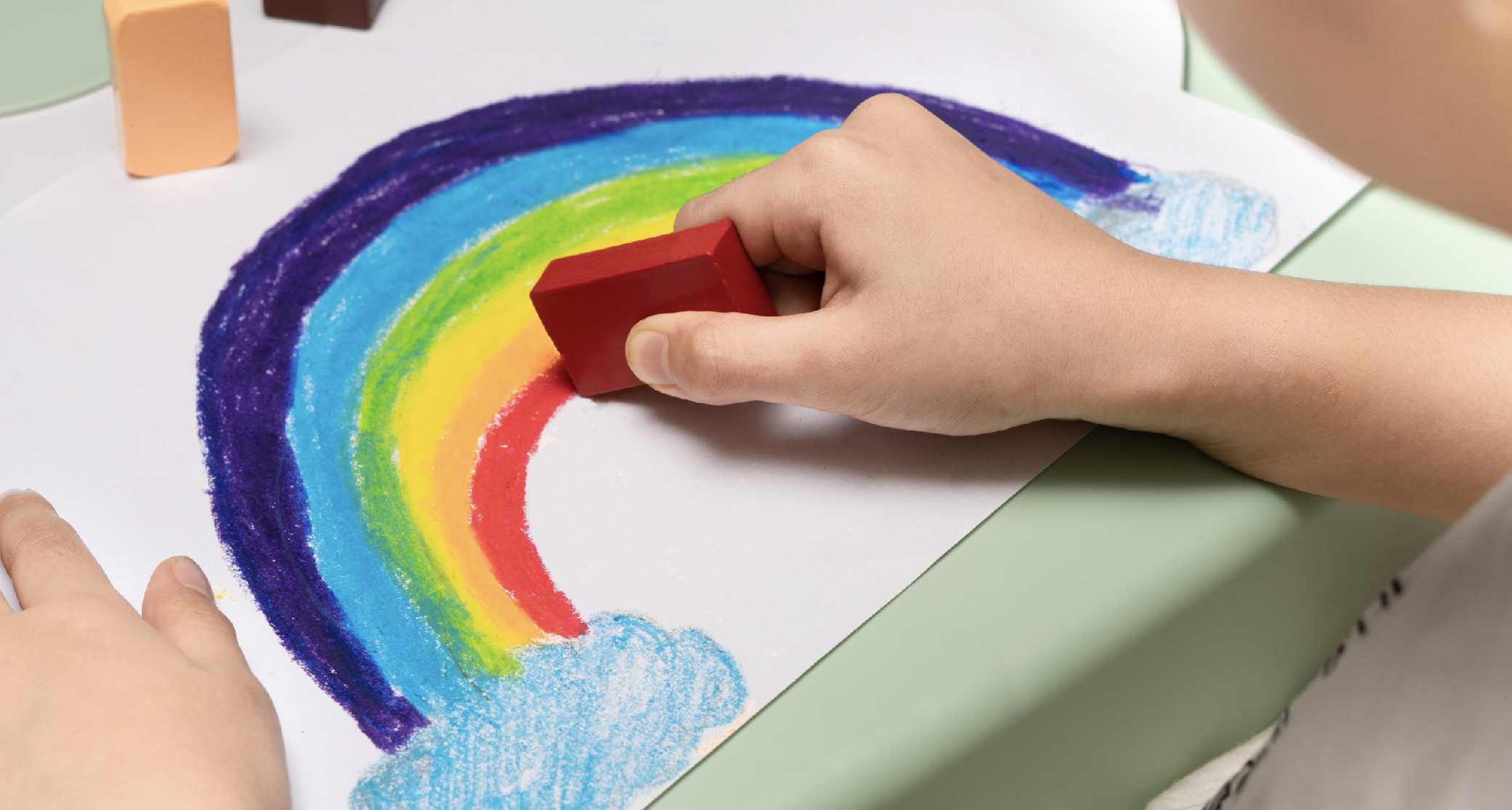 child drawing rainbow using beeswax crayon