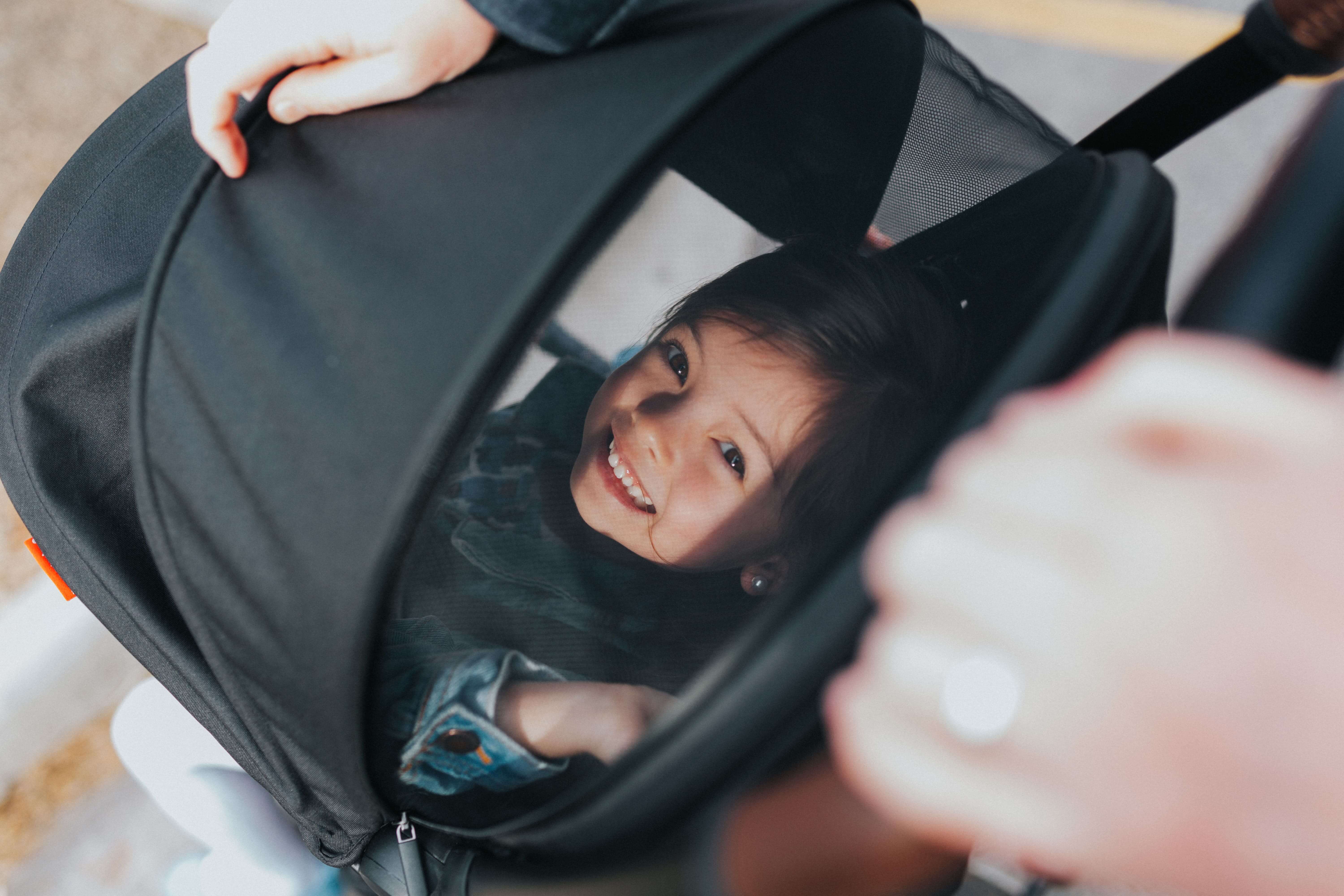 Smiling girl peeking through stroller canopy